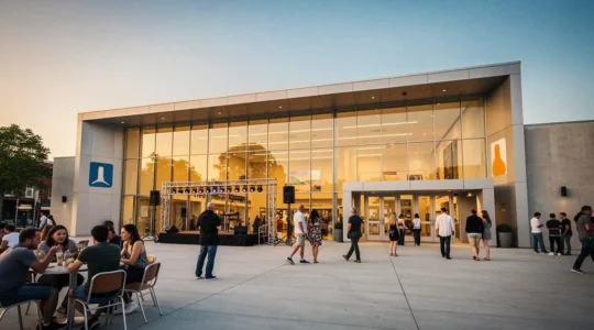 Vue large d'un centre culturel animé au crépuscule, avec des habitants de tous âges circulant entre les espaces, symbolisant le lieu comme cœur vivant du territoire.