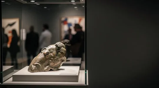 Sculpture antique éclairée délicatement dans une vitrine de conservation, symbole de la tension entre protection patrimoniale et circulation sur le marché de l'art
