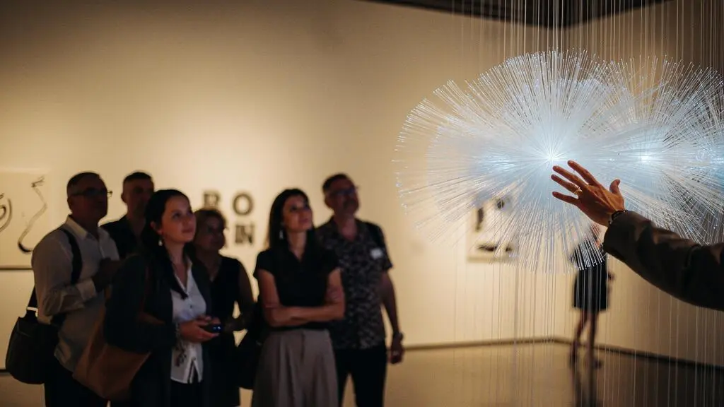 Visiteurs interagissant avec une installation artistique lumineuse et immersive dans une galerie sombre